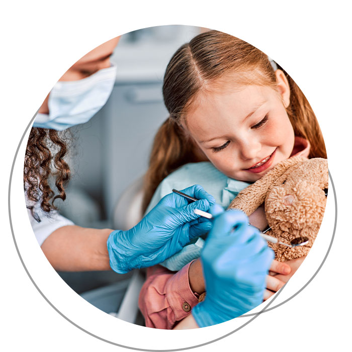 Dentista gioca con bambina durante la visita